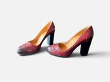 une paire de chaussures rouges et noires posées sur une surface blanche