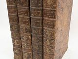 three old books are stacked on top of each other on a white surface
