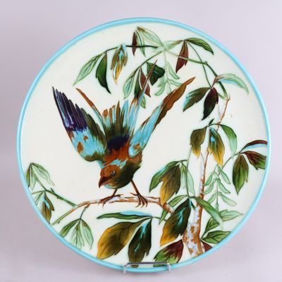 une assiette sur laquelle est peint un oiseau perché sur une branche d'arbre