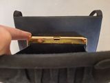 a person holding a black purse with a gold handle