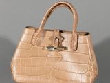 beige alligator skin handbag on grey background with silver hardware