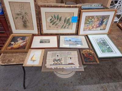 many framed and unframed pictures on a table