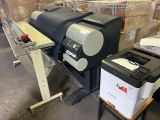 une grande imprimante placée à côté d'une machine d'impression dans un entrepôt