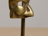 bronze sculpture of a man holding a woman ' s head on top of a table