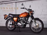 an orange motorcycle parked in front of a white brick wall