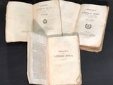 trois livres ouverts posés sur une table l'un à côté de l'autre