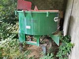 une benne verte posée dans un coin d'un immeuble