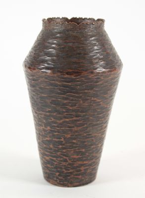 un vase brun posé sur une surface blanche
