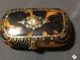 a tortoise shell box with a gold decoration on it