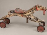 un cheval jouet en bois à l'ancienne, muni de roues, sur fond gris
