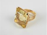 un gros plan d'une bague ornée d'une pierre jaune sur un fond blanc