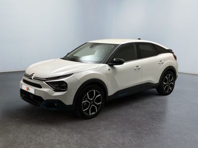 Une voiture blanche est garée dans une pièce au sol noir.
