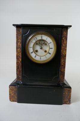 une horloge noire avec un cadran doré sur fond blanc