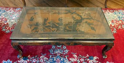 une table basse avec un plateau en verre posée sur un tapis rouge
