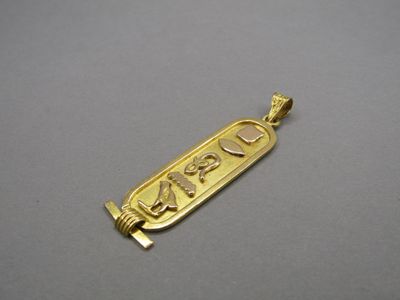 un gros plan d'un pendentif plaqué or sur une surface grise