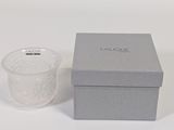 a small glass cup next to a box on a white surface