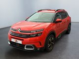 La voiture rouge est garée dans une grande pièce au sol noir.
