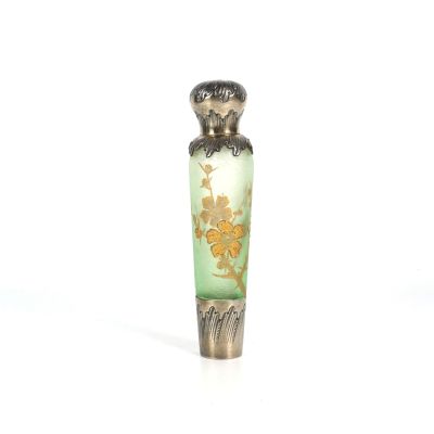 une petite bouteille en verre ornée d'un motif doré et vert