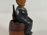 a figurine of a man sitting on a barrel holding a bottle of wine