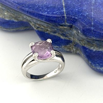 an image of a pink sapphire and diamond ring sitting on a rock