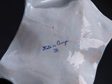 a close up of a white porcelain object with blue writing on it