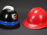 pair of red and black fireman ' s hats on a black background