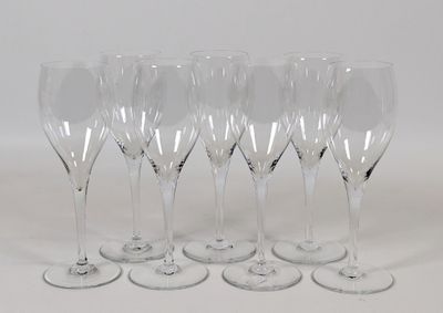 six verres à vin transparents alignés sur une surface blanche
