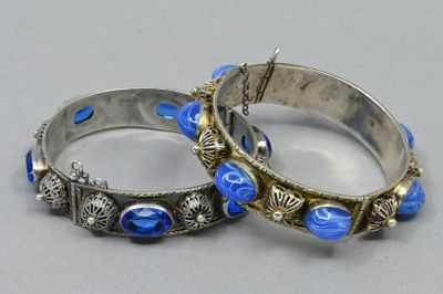 pair of silver bangles with blue glass beads on a gray surface