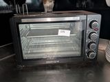 un four grille-pain posé sur un plan de travail, à côté d'une pile d'assiettes