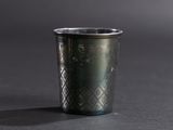 un gros plan d'une tasse en métal posée sur une surface noire
