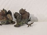 two figurines of birds sitting on a white surface