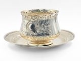 une tasse et une soucoupe en argent posées sur une soucoupe