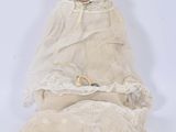 an old doll with a white dress and bonnet sitting on a white surface