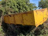 a yellow dump truck sitting in the middle of a field