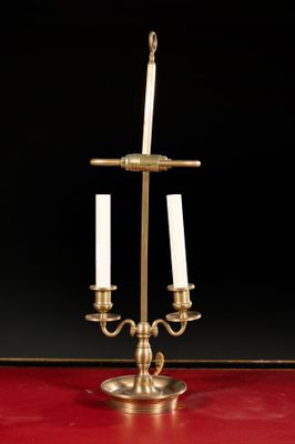 an antique brass candelab with three candles on a red table