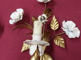 two wall sconces with flowers on them on a red surface