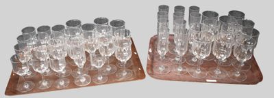 une paire de verres à vin transparents posés sur un socle en bois, sur fond gris