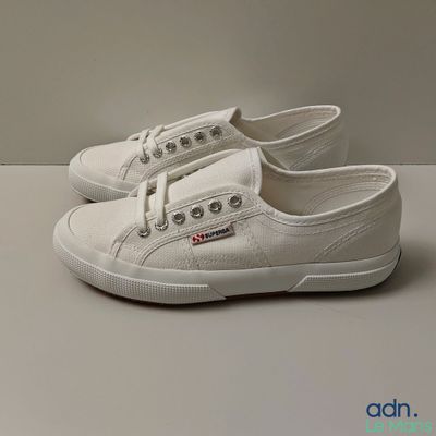 white canvas sneakers with laces on the side of them on a white surface