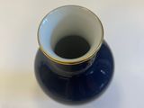 a blue vase with a gold rim sitting on a white surface