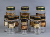 six bocaux en verre remplis de différents types de médicaments, posés sur une surface blanche