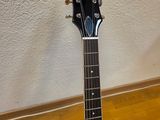 an electric guitar sits on a stand on a wooden floor
