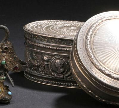 une boîte en argent et une figurine en argent posées l'une à côté de l'autre