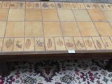 une table en bois avec un plateau en carrelage, posée sur un tapis