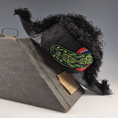 un chapeau noir orné d'un cornichon, posé sur une boîte