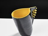 a black and yellow vase sitting on a white table