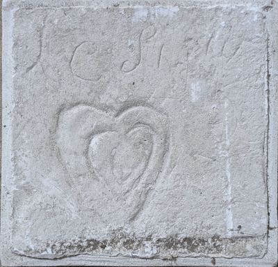 un parpaing sur lequel est gravé un cœur, posé sur un trottoir