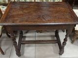 a wooden table with two chairs and a couch in the background
