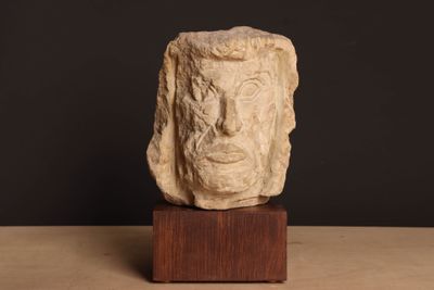 sculpture représentant le visage d'un homme, posée sur un socle en bois