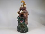 a figurine of a woman sitting on a rock