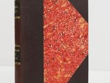 un vieux livre à la couverture rouge et à la reliure noire